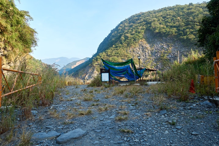 Open rocky area with two small pools with a tarp overhead